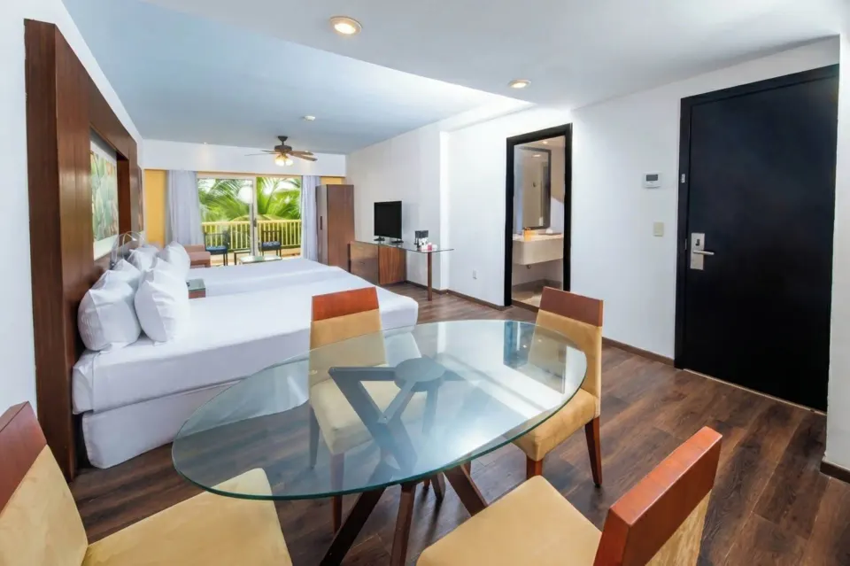 Deluxe Tropical Room View with two beds, table, and balcony at Krystal Grand Nuevo Vallarta.