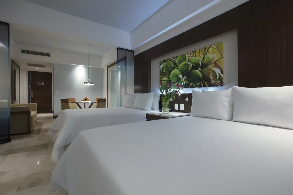 Junior Suite Pool View Doble with two white beds and tropical wall art at Krystal Grand Nuevo Vallarta.