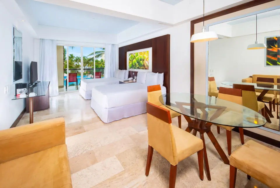 Junior Suite Pool View with balcony, two beds, and dining area at Krystal Grand Nuevo Vallarta.