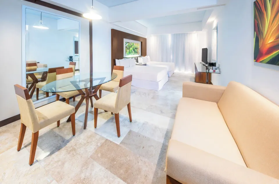 Junior Suite Pool View with sofa, dining table, and two beds at Krystal Grand Nuevo Vallarta.