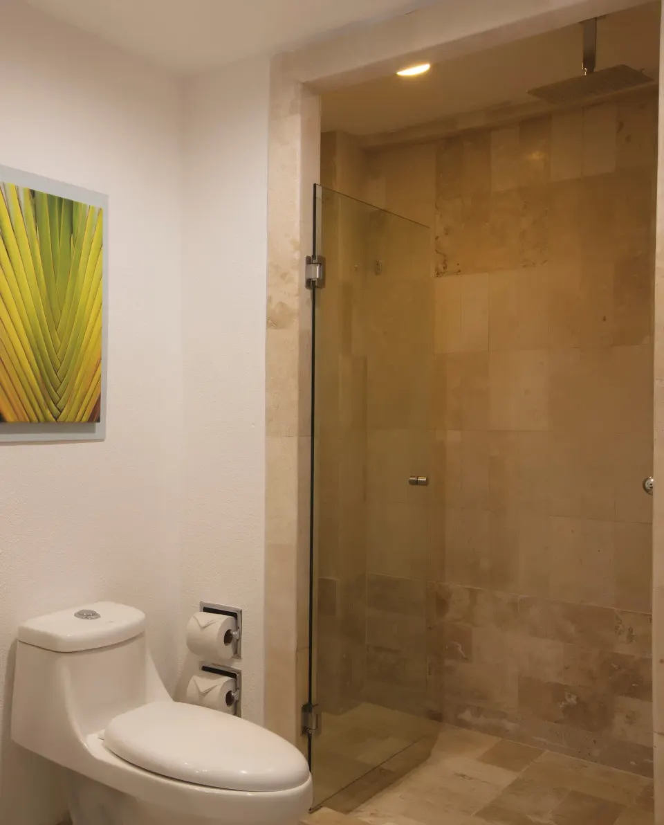 Standard room bathroom with toilet and glass shower at Krystal Grand Nuevo Vallarta.