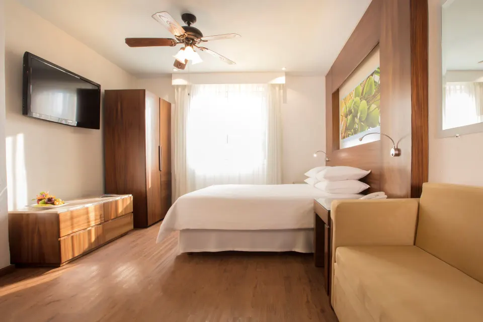 Standard room with king bed, TV, wardrobe, and sofa at Krystal Grand Nuevo Vallarta.