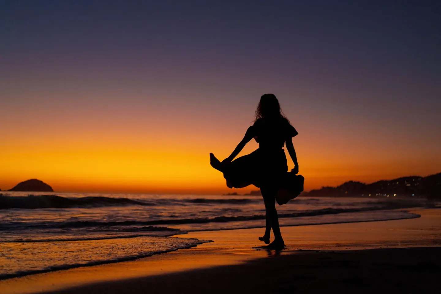A silhouetted person stands on the beach at sunset near Krystal Ixtapa.