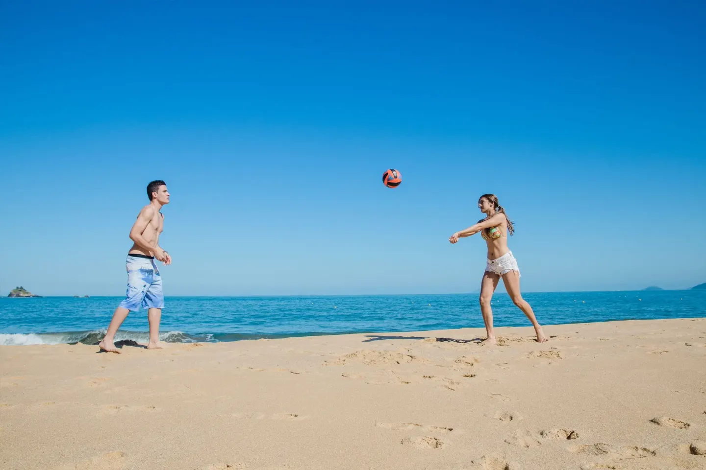 Two guests playing beach volleyball by the ocean at Krystal Ixtapa.