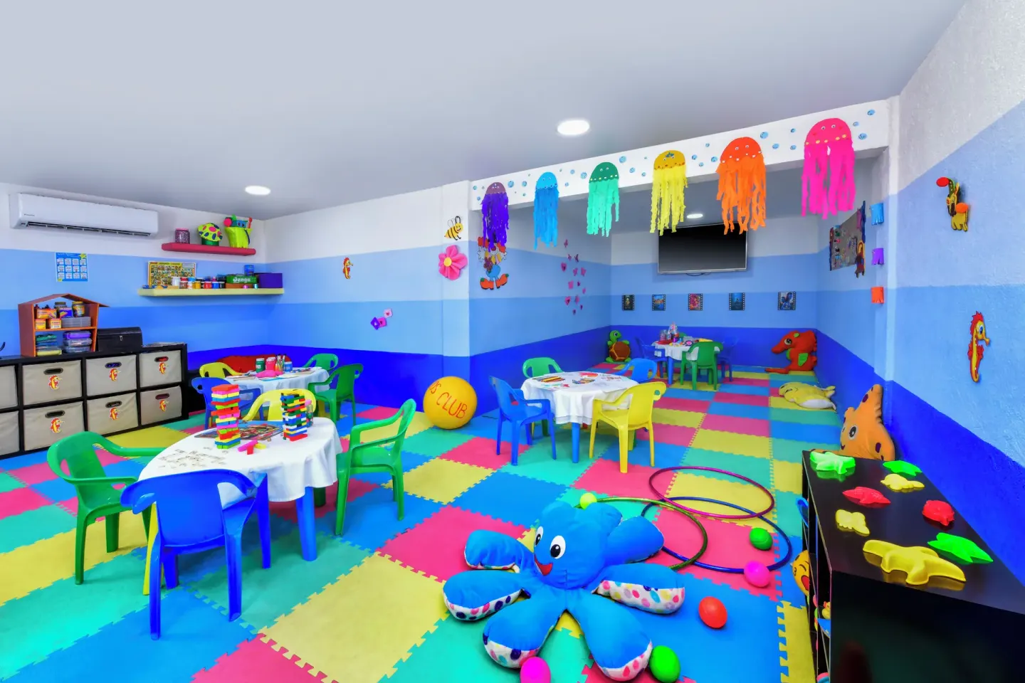 A colorful kids club room with toys, small tables, and foam flooring at Krystal Ixtapa.