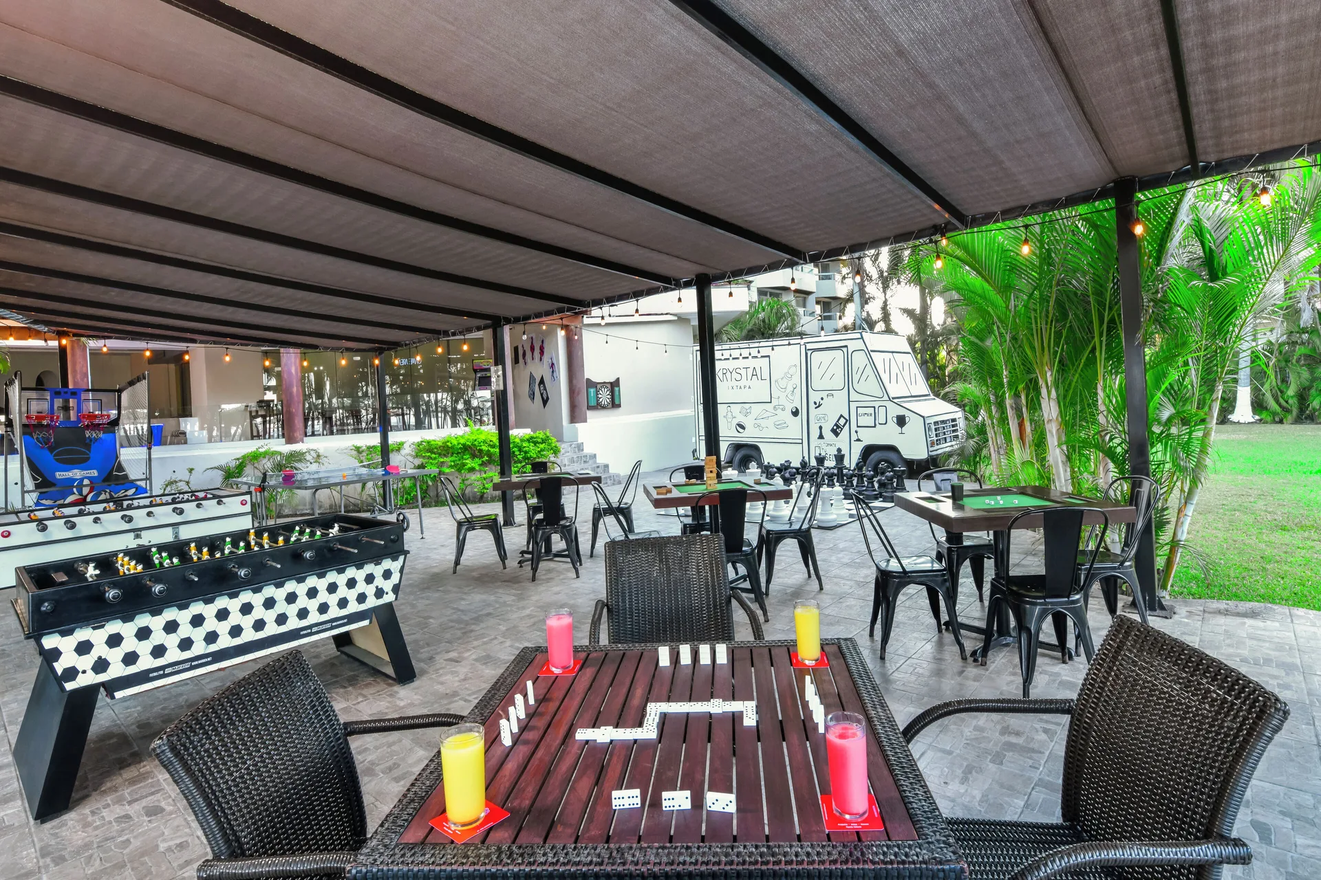 Covered game tables with foosball, chess, and dominoes sit outdoors at Krystal Ixtapa.
