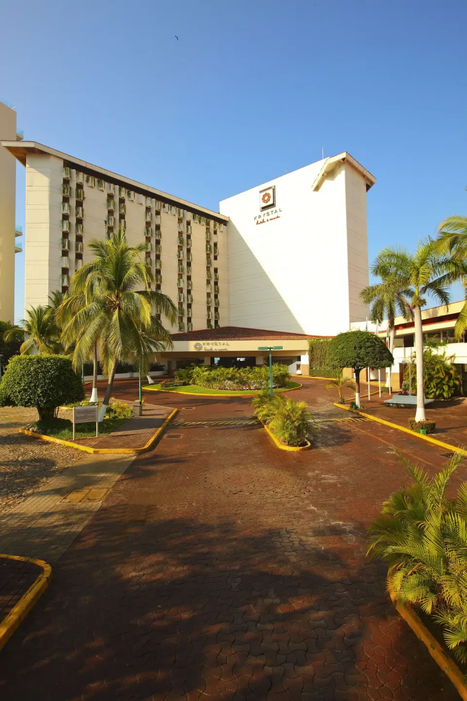 Front drive and tower exterior with palms at Krystal Ixtapa.