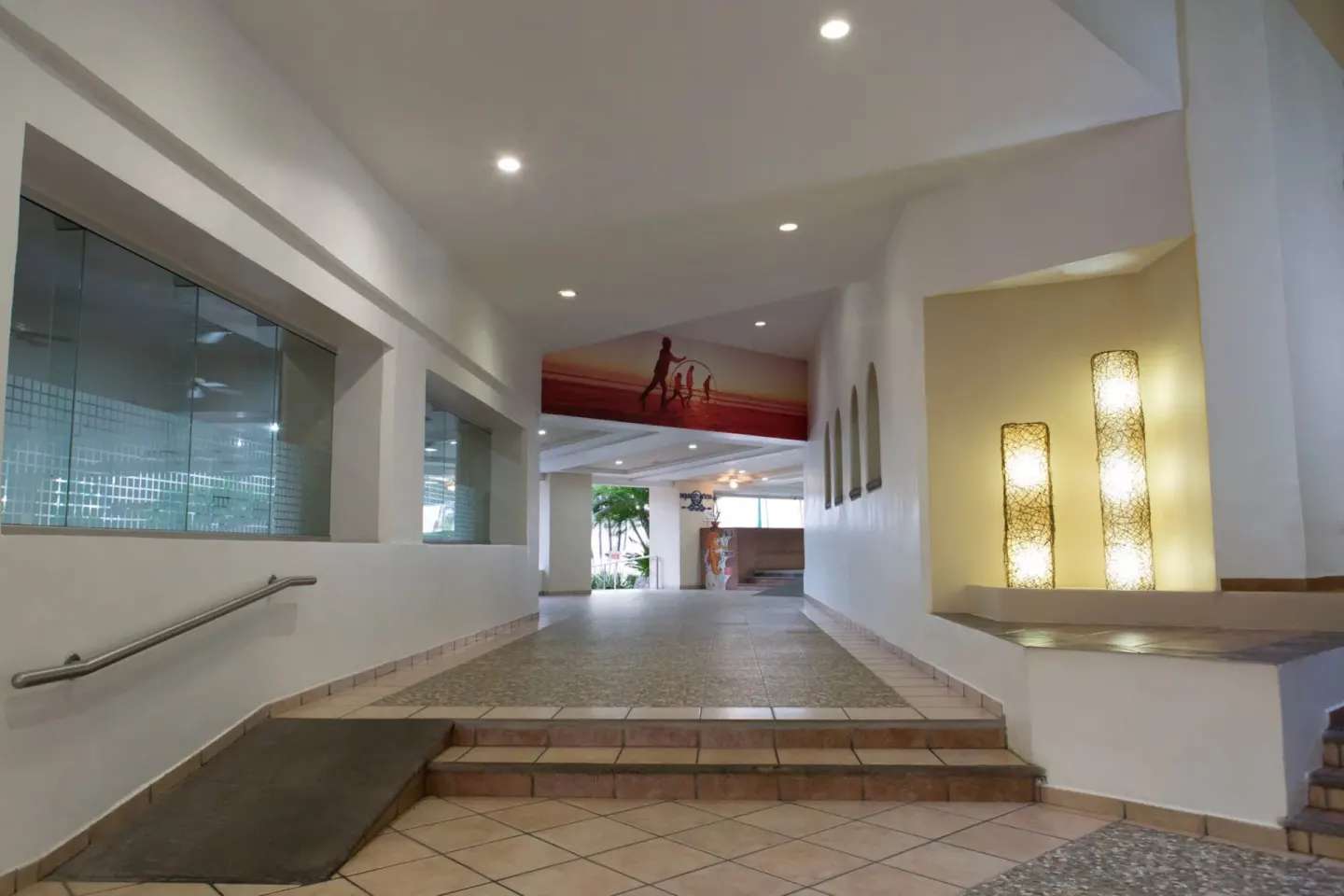 Tiled lobby corridor with steps, ramp, and lit wall niches at Krystal Ixtapa.