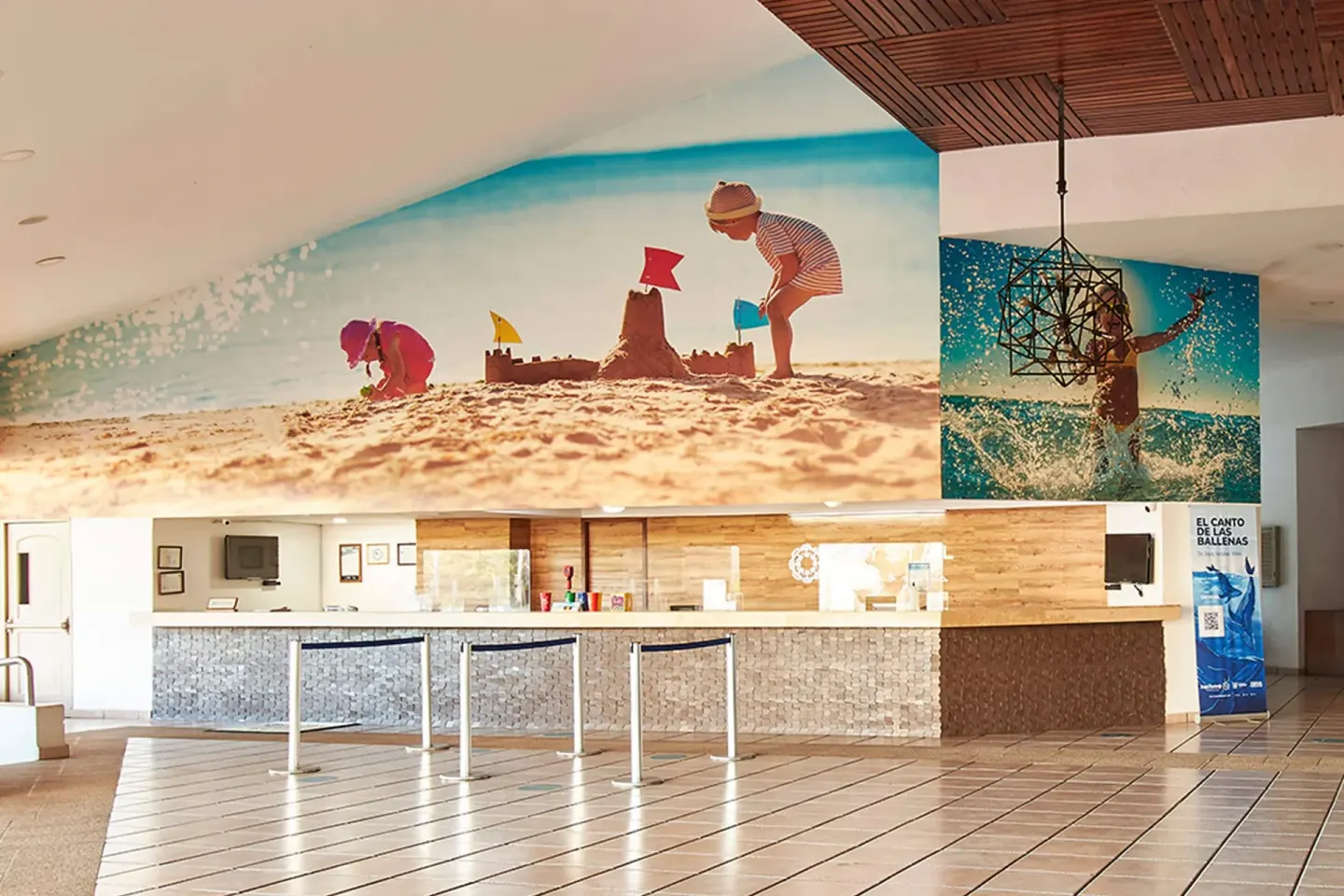 Wide reception area with beach mural, tiled floor, and queue lanes at Krystal Ixtapa.