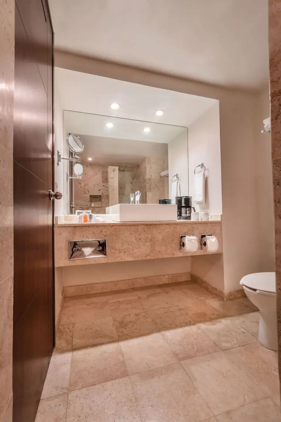 Standard room bathroom with wide vanity, mirror and toilet at Krystal Ixtapa.