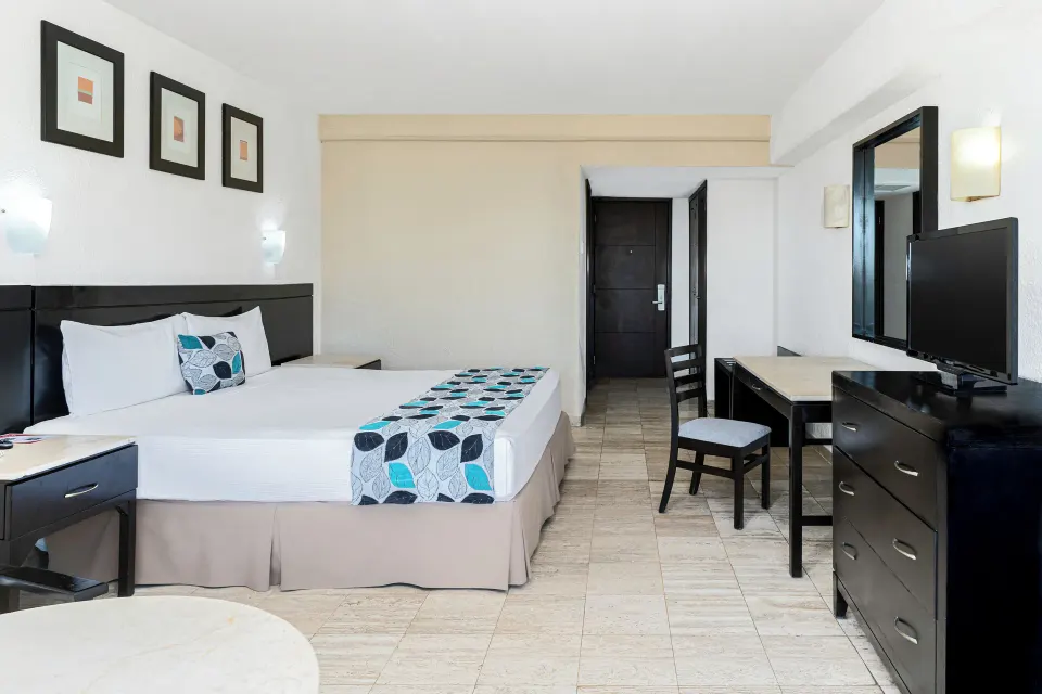 Standard Room Garden View with one bed, dresser, TV and desk at Krystal Ixtapa.