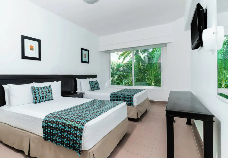 Standard Room Garden View with two beds and leafy window view at Krystal Ixtapa.