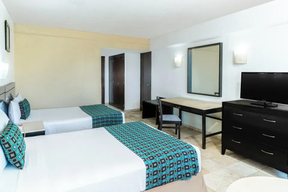 Standard Room Garden View with two beds, turquoise runners and desk at Krystal Ixtapa.