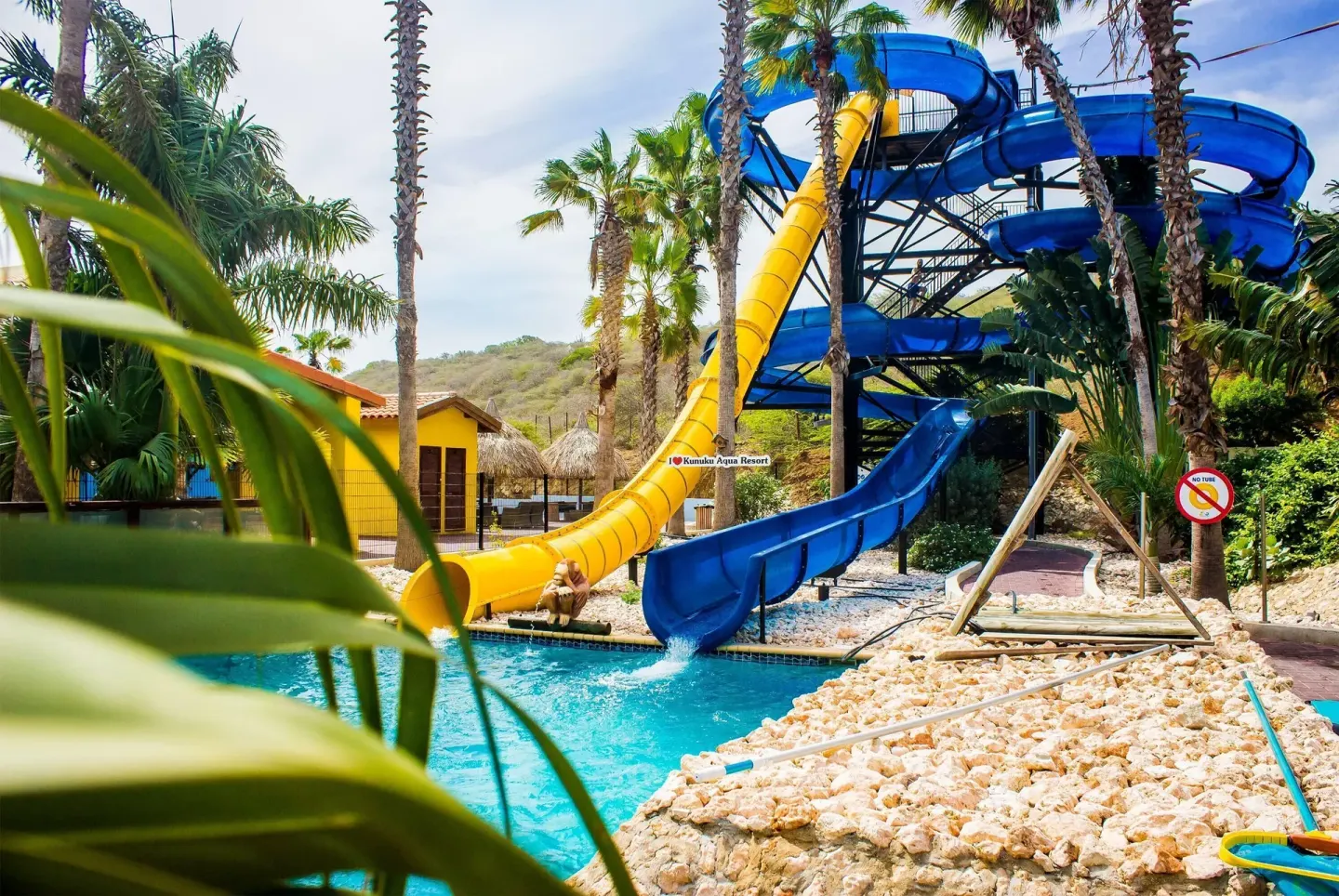 Blue and yellow waterslides dropping into a pool at Kunuku Resort Curacao.