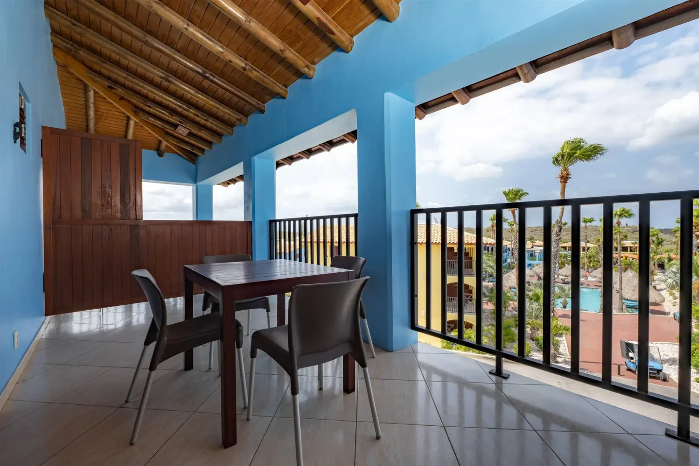 Covered balcony with dining table and resort view at Kunuku Resort Curacao.