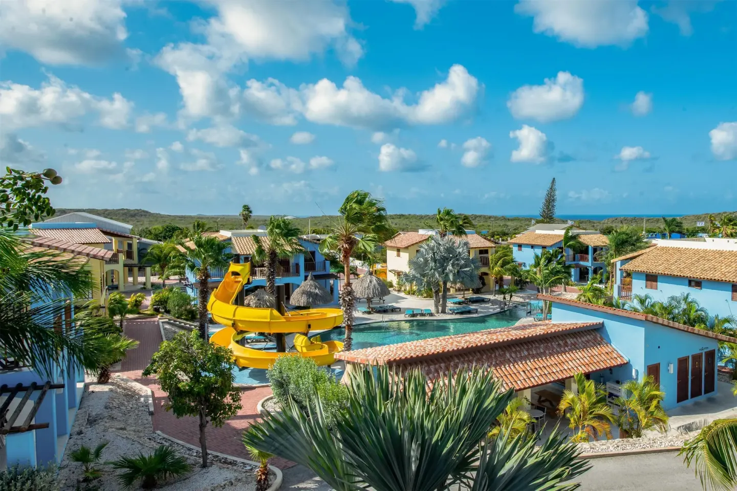 Elevated resort view with yellow waterslide and colorful buildings at Kunuku Resort Curacao.