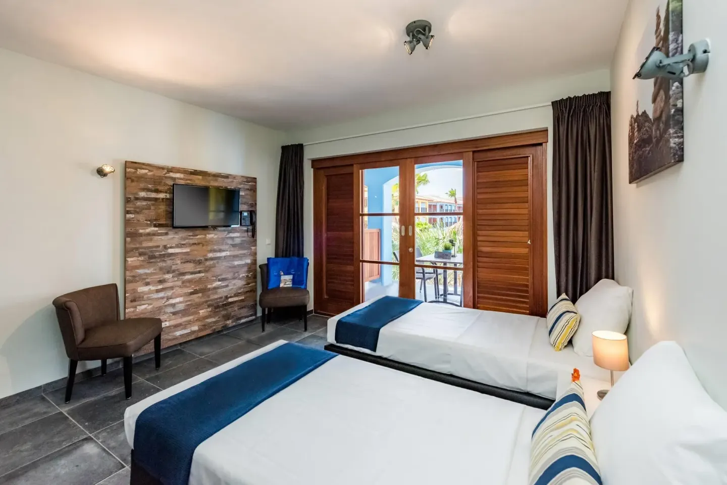 Guest room with two twin beds and balcony doors at Kunuku Resort Curacao.
