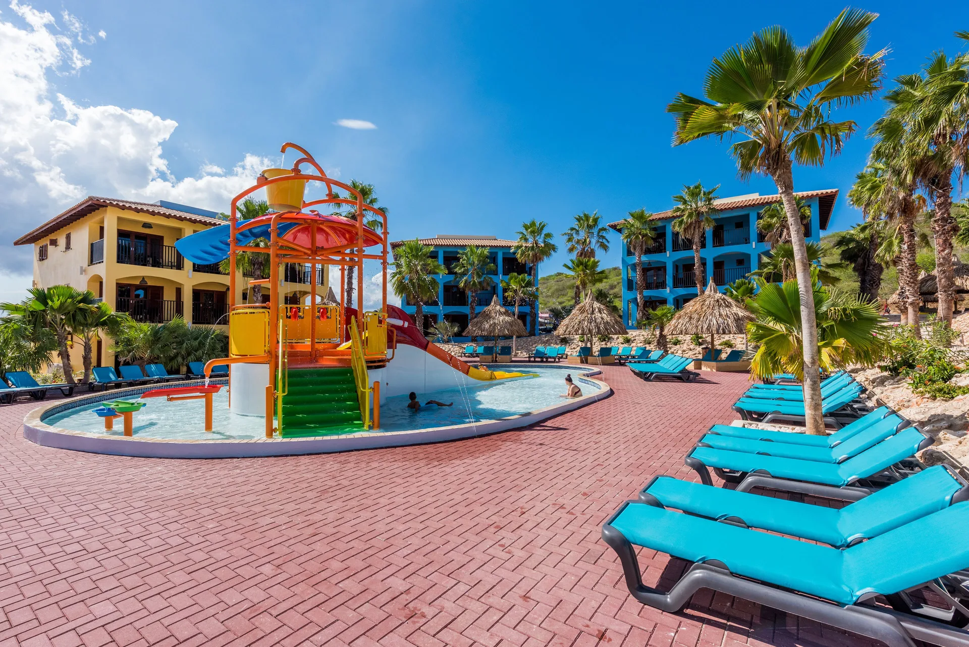 Kids splash pool with loungers and palm trees at Kunuku Resort Curacao.