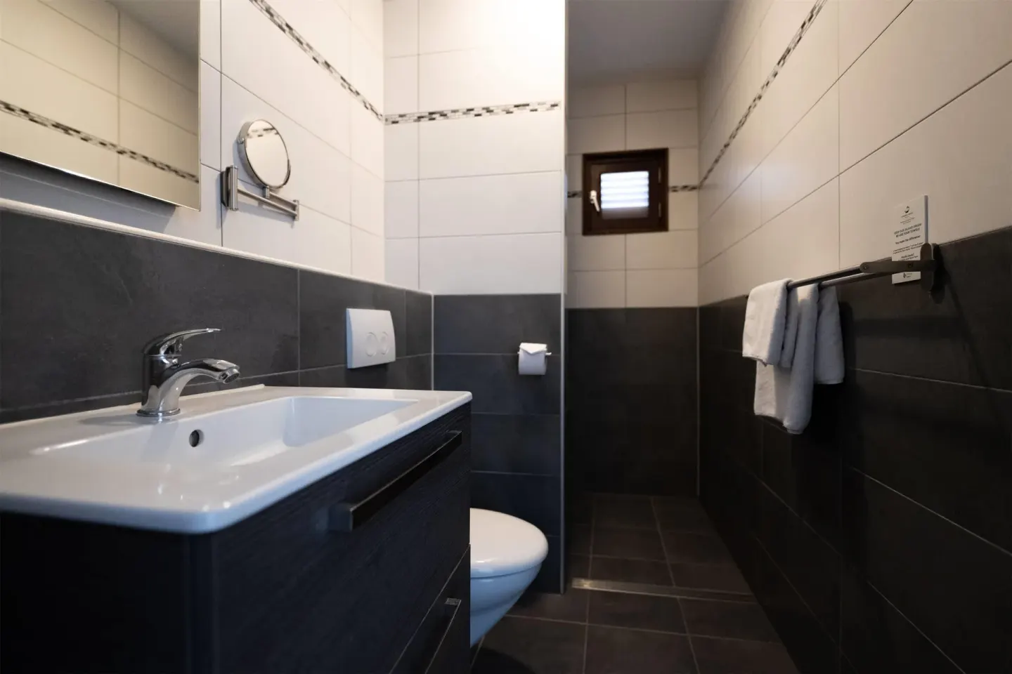 Narrow tiled bathroom with vanity, toilet, and towel rail at Kunuku Resort Curacao.