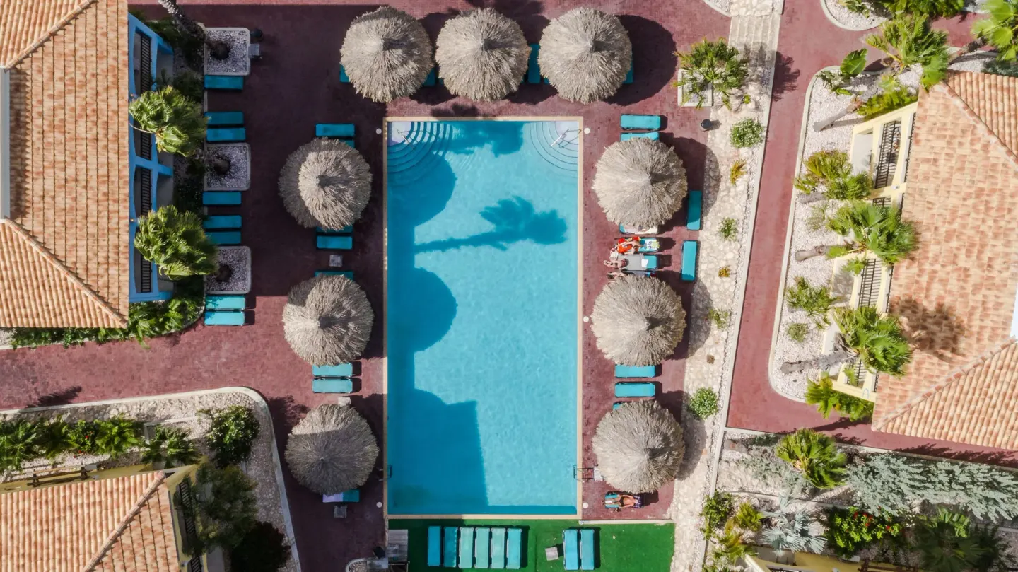 Overhead view of a rectangular pool with palapas and loungers at Kunuku Resort Curacao.