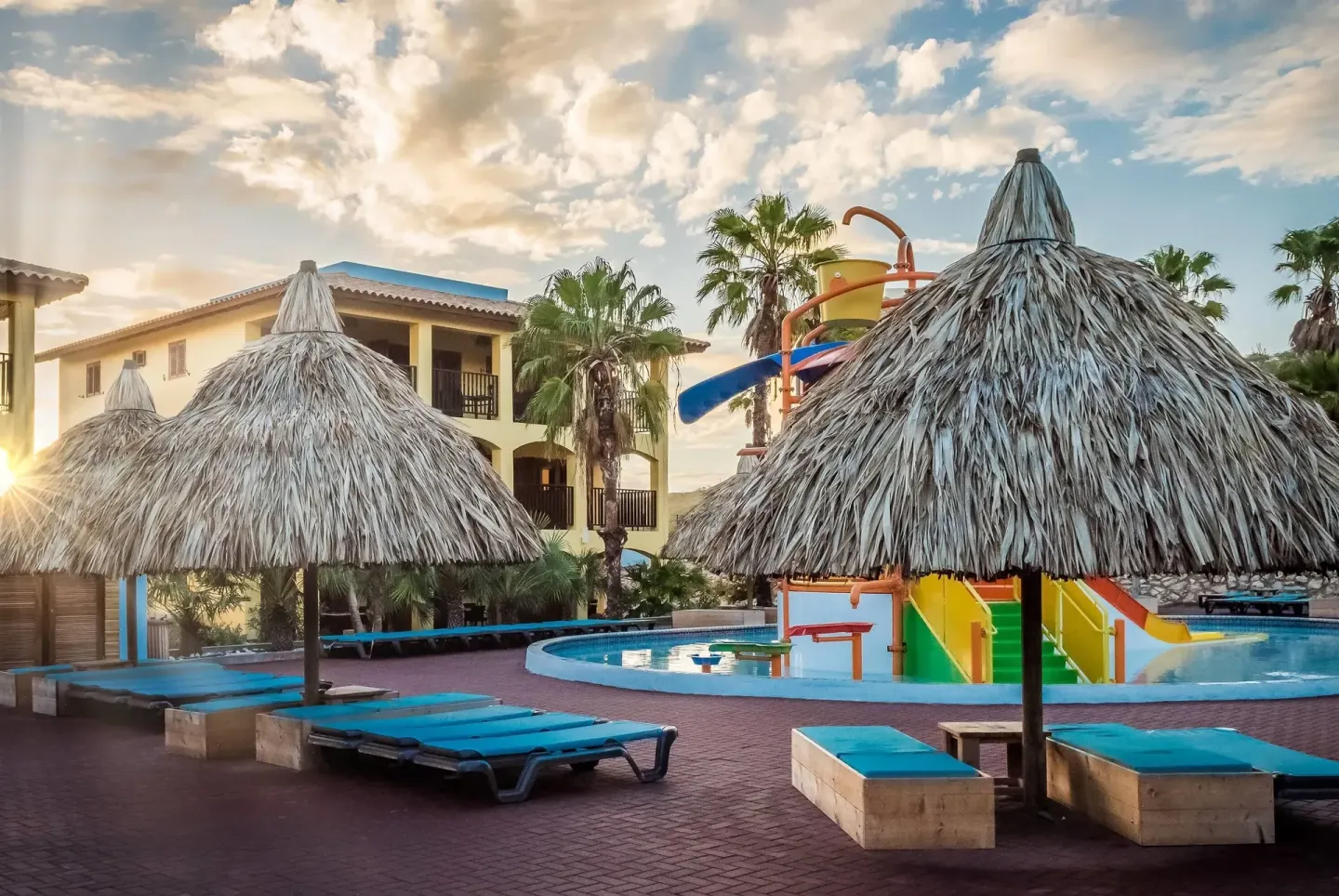 Poolside palapas, loungers, and a water-play area at Kunuku Resort Curacao.
