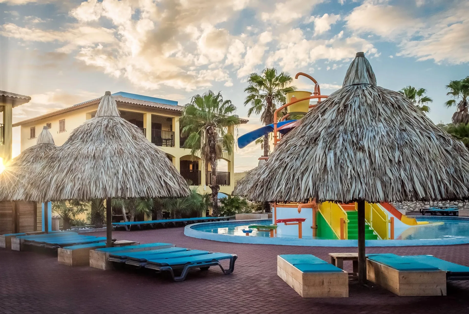 Poolside palapas, loungers, and a water-play area at Kunuku Resort Curacao.