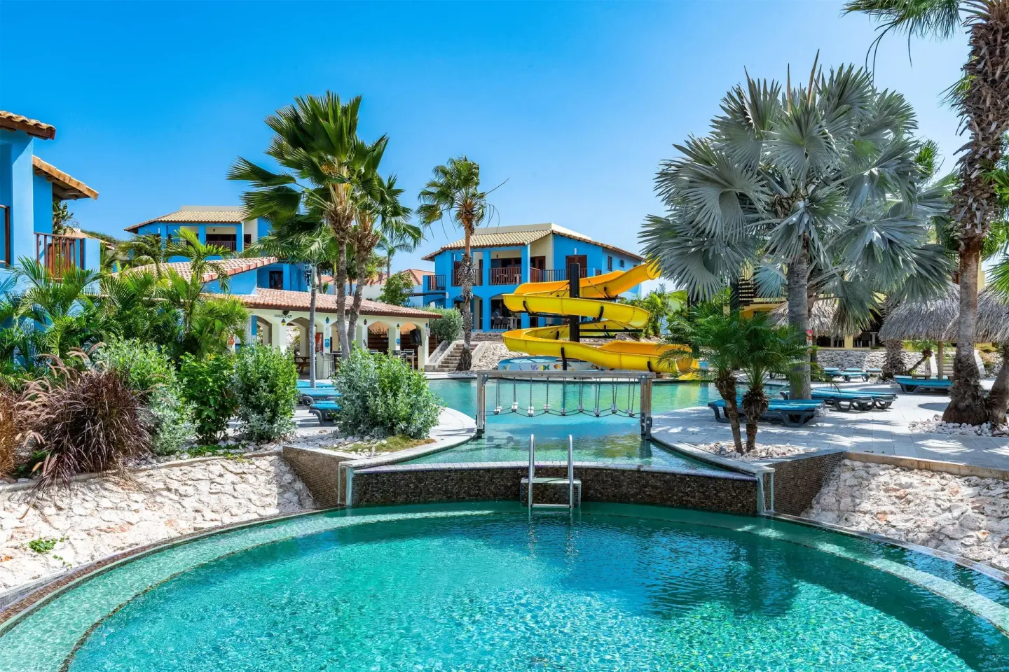 Resort pool with yellow waterslide and tropical landscaping at Kunuku Resort Curacao.