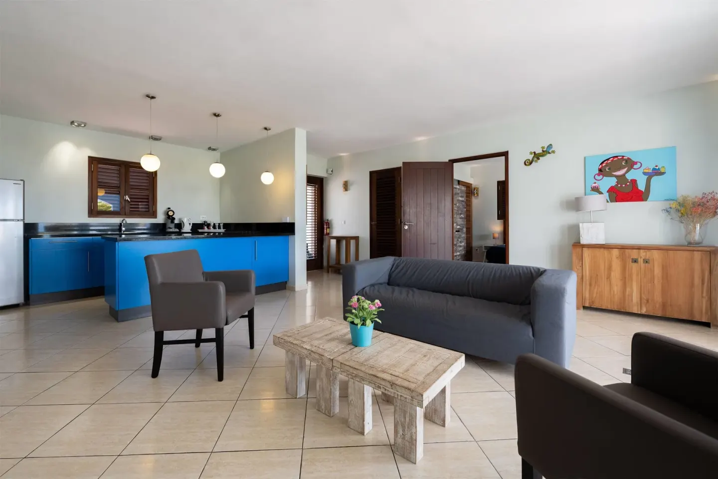 Living area with sofa, chairs, and blue kitchen at Kunuku Resort Curacao.
