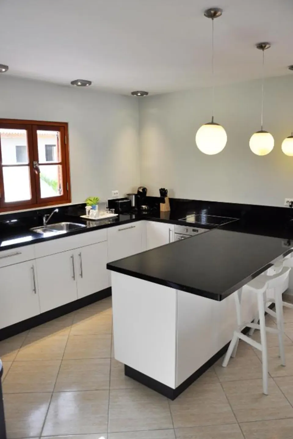 Apartment kitchen with island, black counters, and white stools at Kunuku Resort Curacao.