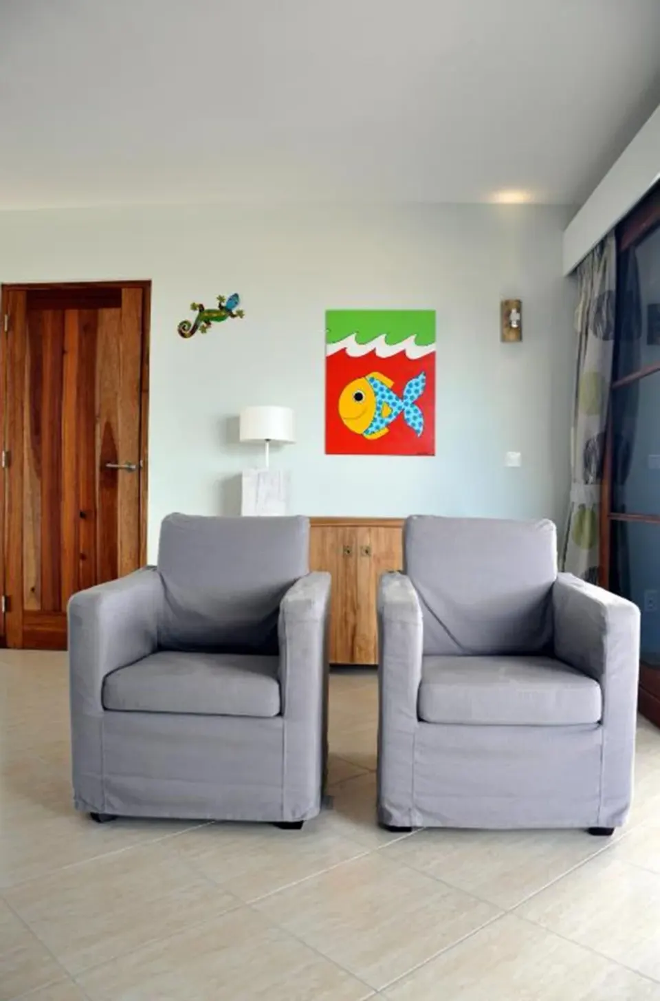 Two gray armchairs and colorful wall art in the apartment at Kunuku Resort Curacao.