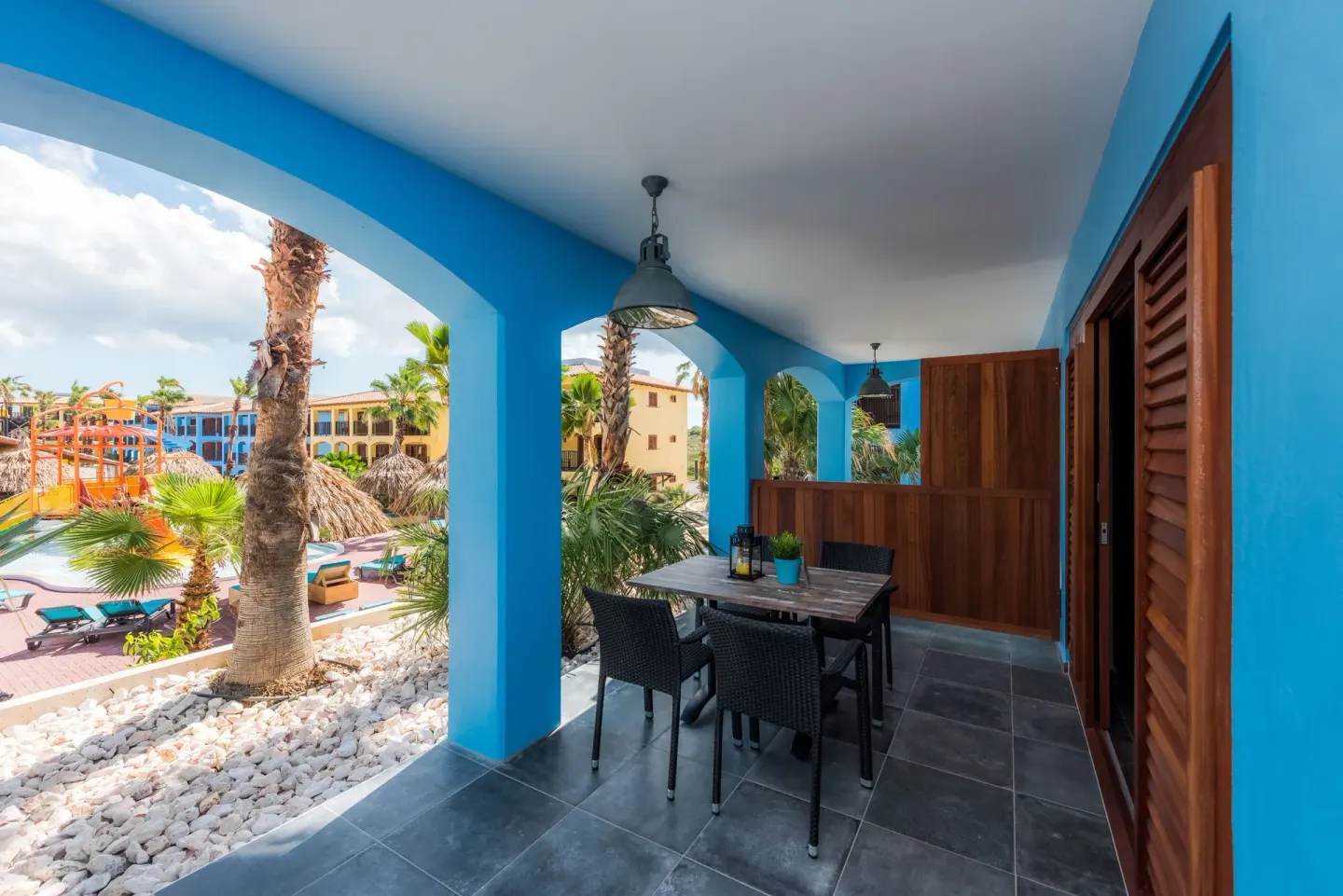 Family Quadruple Room terrace with table and resort water park view at Kunuku Resort Curacao.