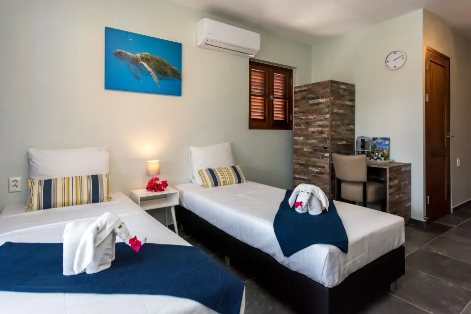 Family Quadruple Room twin beds with blue throws at Kunuku Resort Curacao.