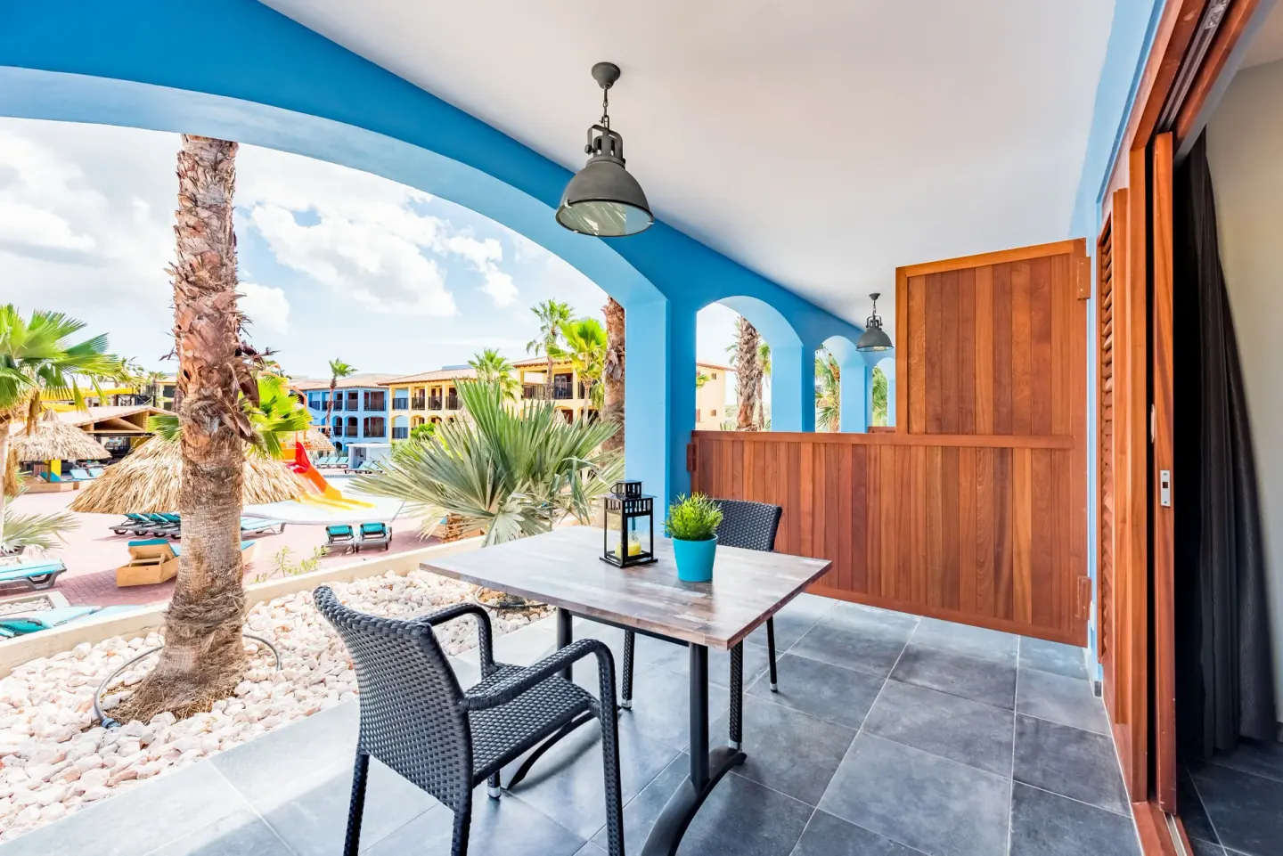 Standard Room terrace with table and resort pool view at Kunuku Resort Curacao.