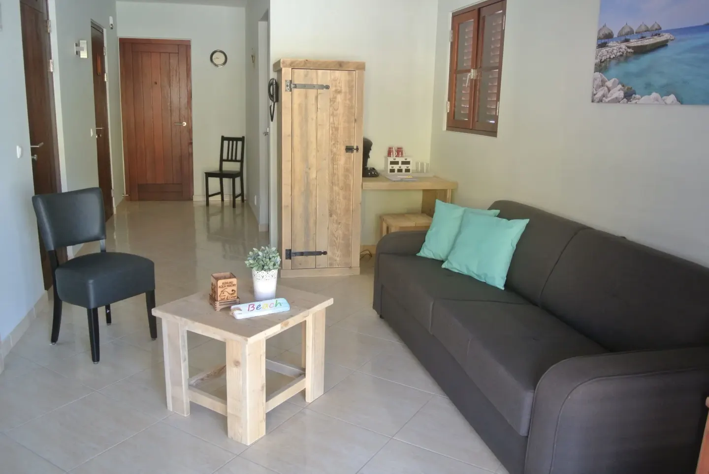 Suite living room with sofa, coffee table, chair, and wooden cabinet at Kunuku Resort Curacao.