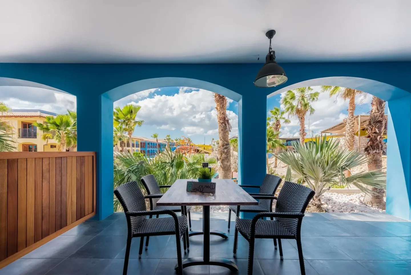 Suite patio with table, chairs, blue arches, and garden view at Kunuku Resort Curacao.