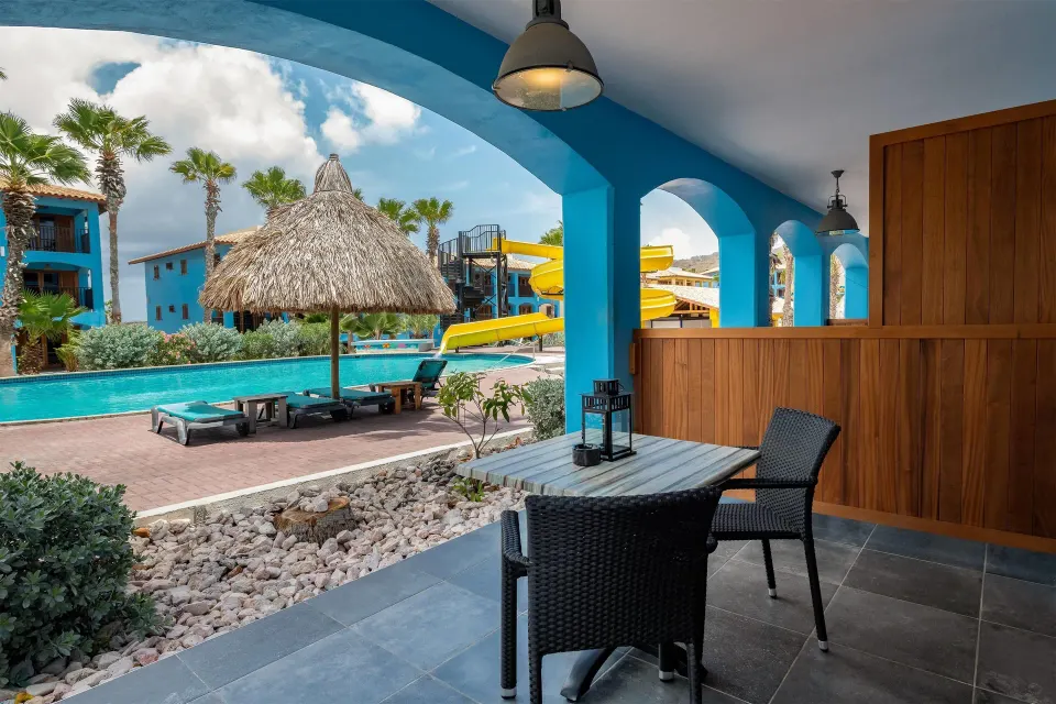 Suite terrace with seating beside the pool and water slides at Kunuku Resort Curacao.