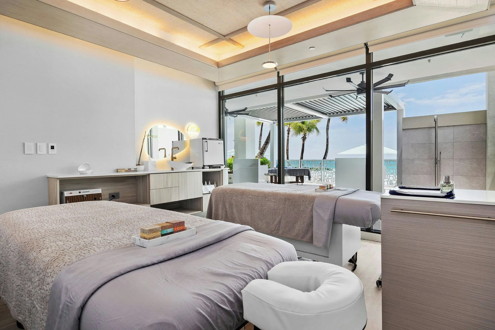 Couples massage room with two tables and ocean-facing glass doors at La Concha Resort, Puerto Rico.