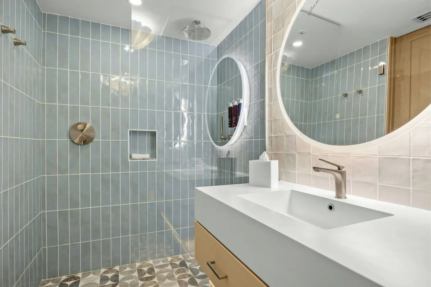 Guest bathroom with tiled shower, round mirrors, and white vanity at La Concha Resort, Puerto Rico.
