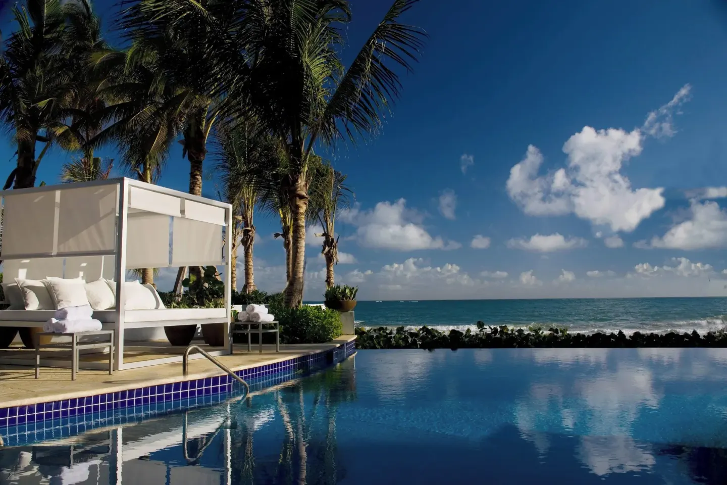 Oceanfront infinity pool cabana with palm trees at La Concha Resort, Puerto Rico.