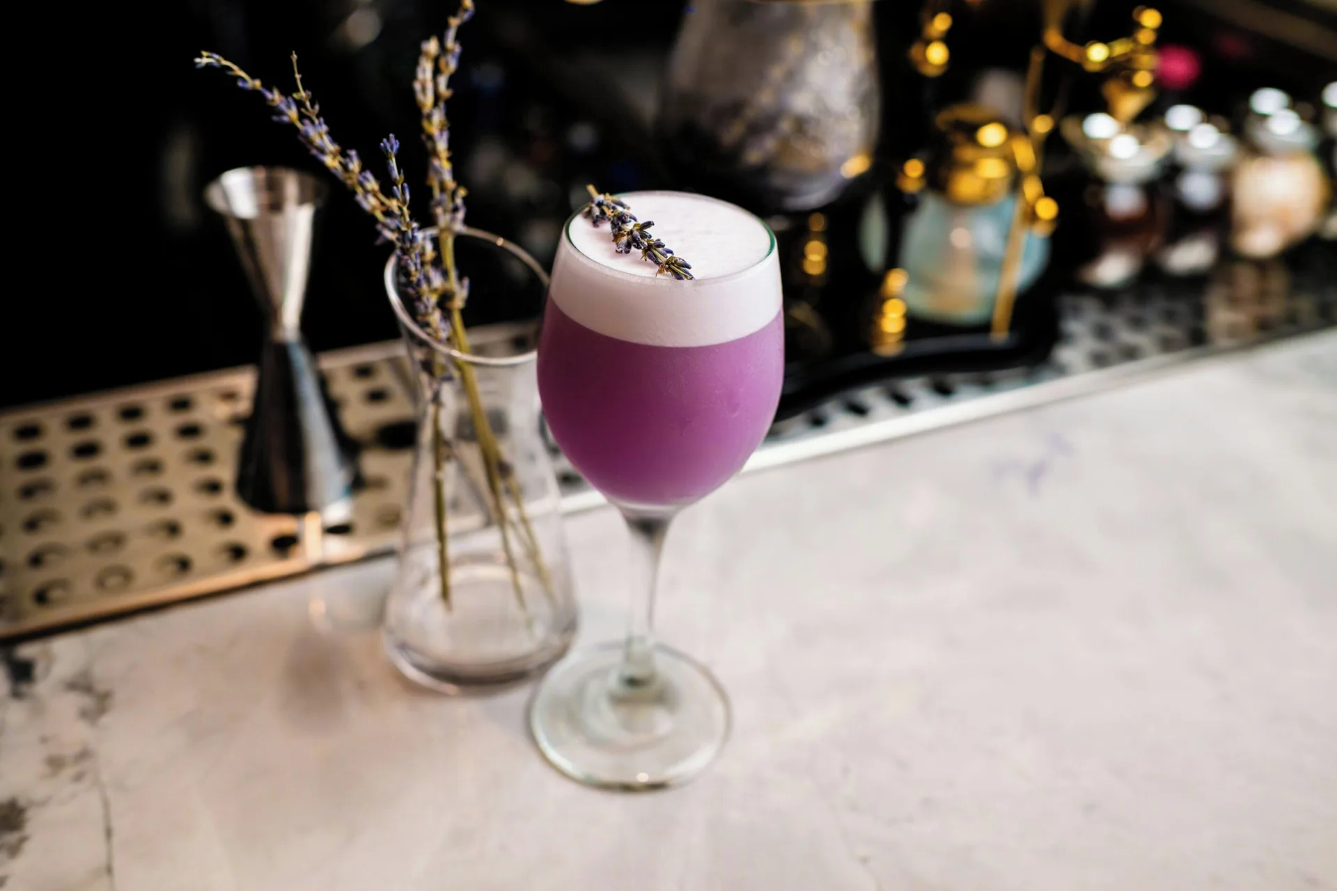 Purple foamy cocktail with lavender garnish on a bar at La Concha Resort, Puerto Rico.