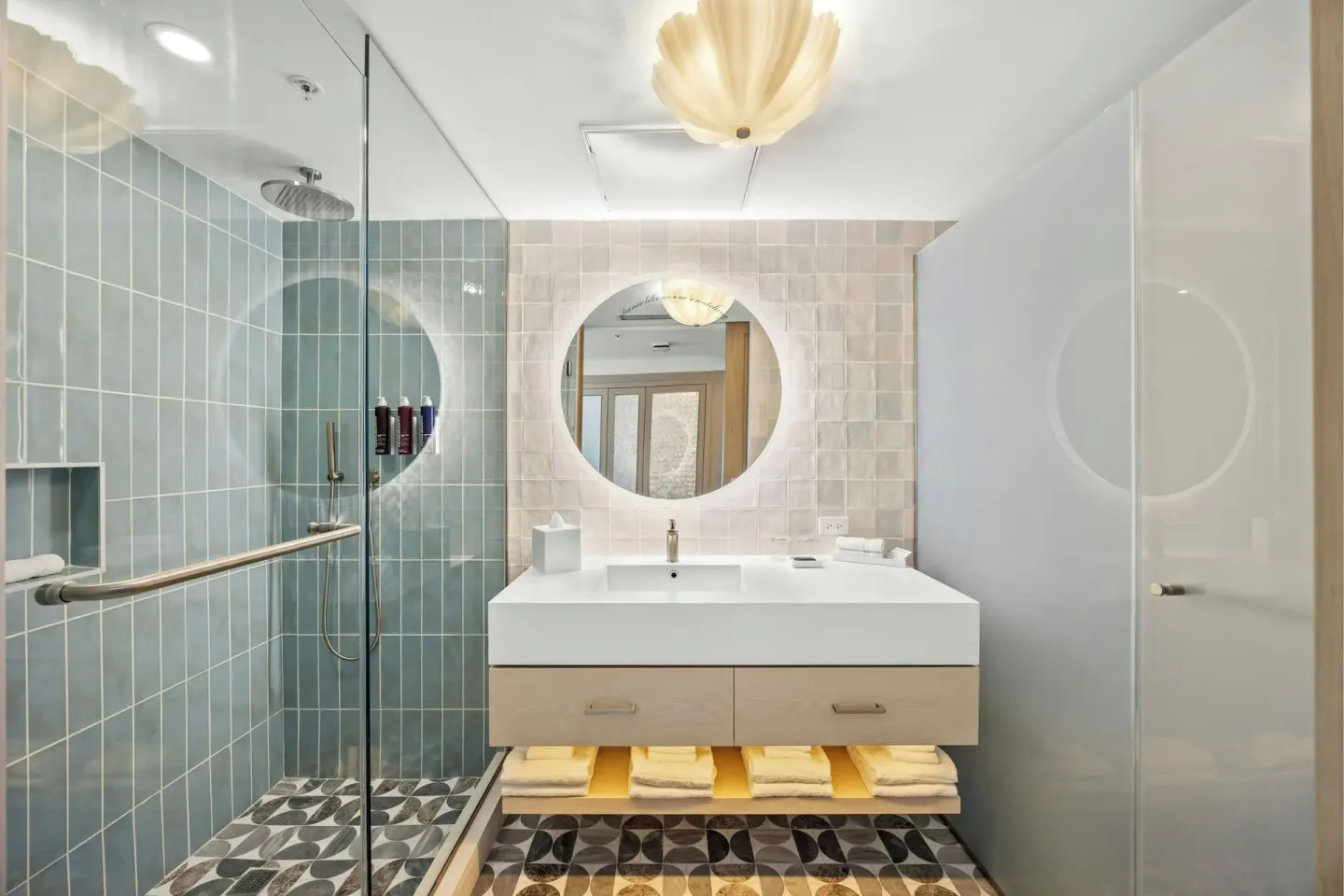 Deluxe Suite bathroom with glass shower and round mirror at La Concha Resort, Puerto Rico.