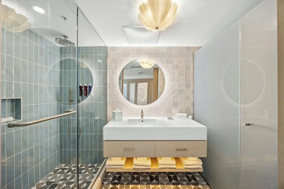 Deluxe Suite bathroom with glass shower and round mirror at La Concha Resort, Puerto Rico.