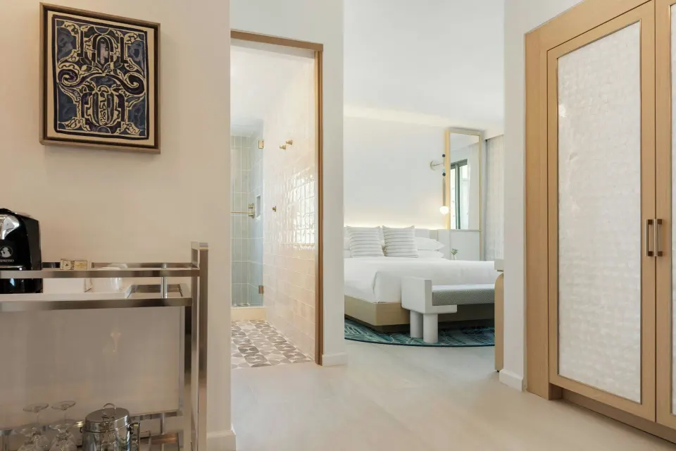 Entry area with minibar cart, wardrobe, bathroom doorway, and bed at La Concha Resort, Puerto Rico.