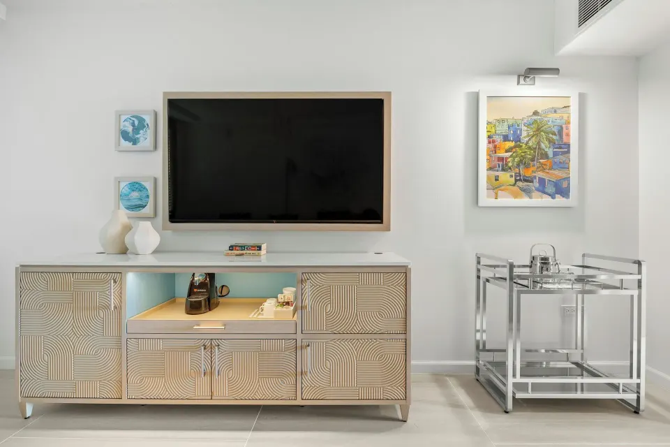 TV wall, patterned cabinet, coffee station, and bar cart in a room at La Concha Resort, Puerto Rico.