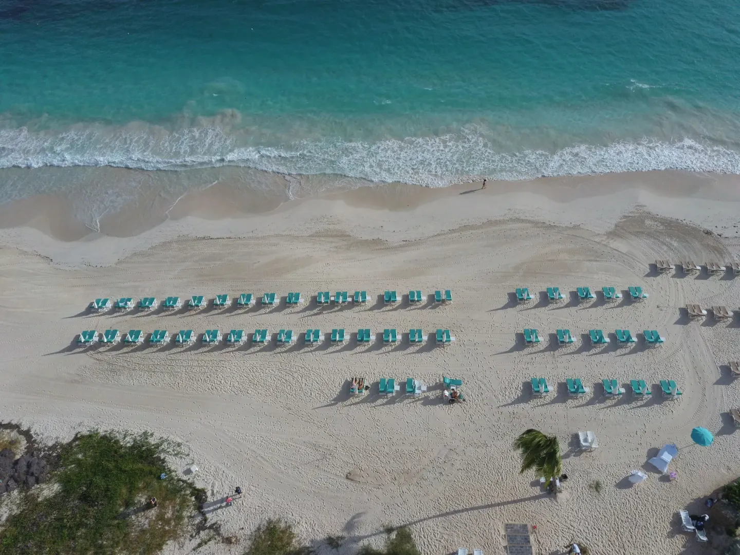 Aerial view of beach loungers lined up by the surf at La Playa Orient Bay.