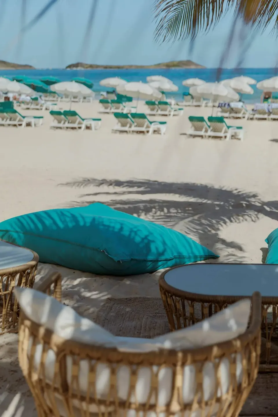 Beach lounge seating and turquoise cushions on the sand at La Playa Orient Bay.