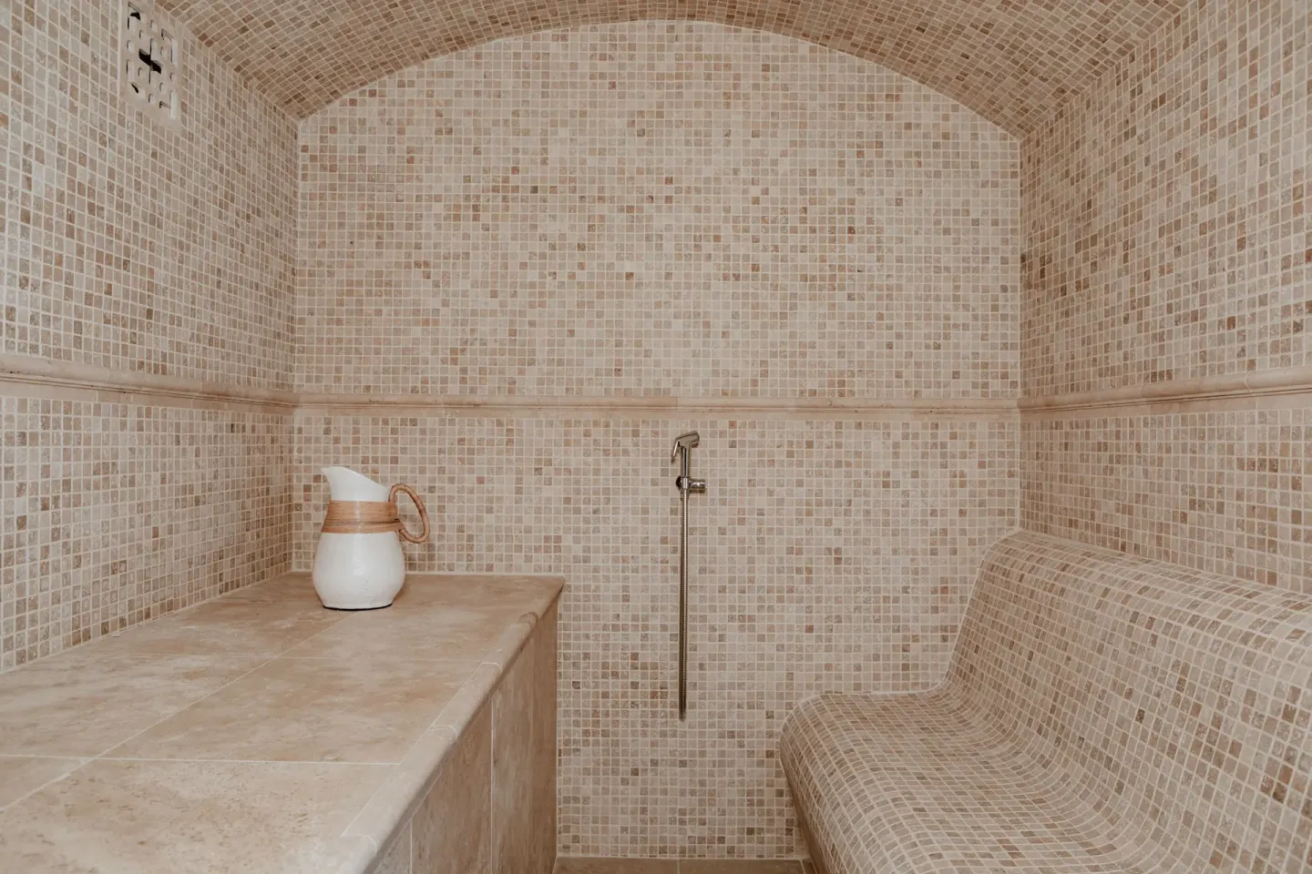 Mosaic-tiled steam room with curved bench and hand shower at La Playa Orient Bay.