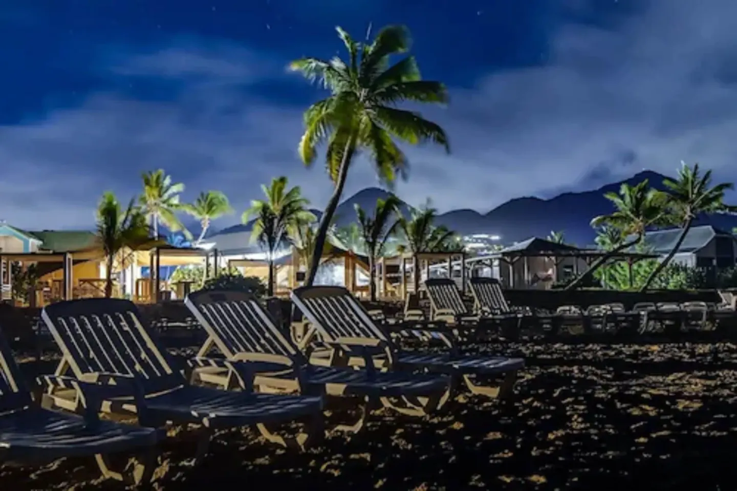 Nighttime beach loungers under palm trees at La Playa Orient Bay.