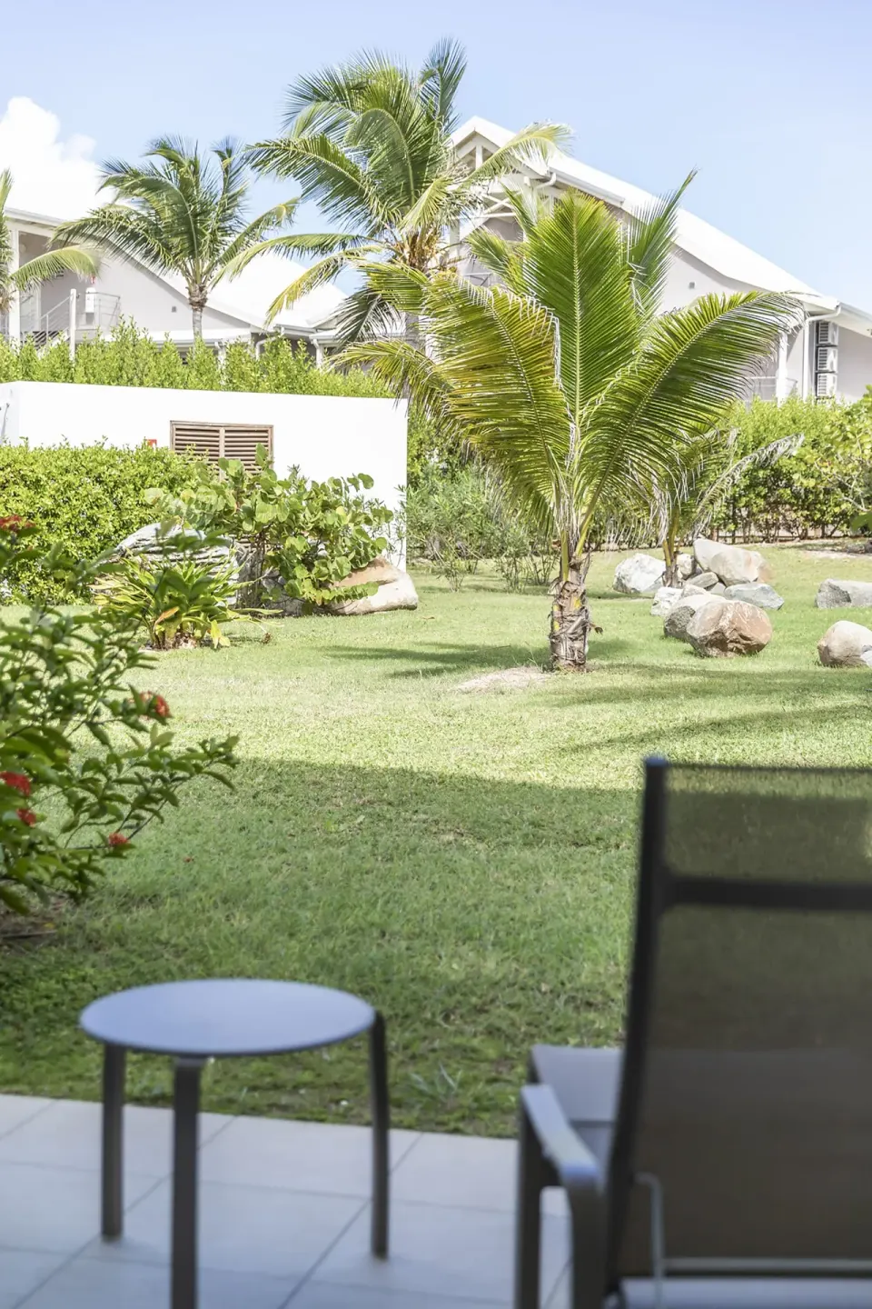 Patio chair and table facing a palm garden at La Playa Orient Bay.