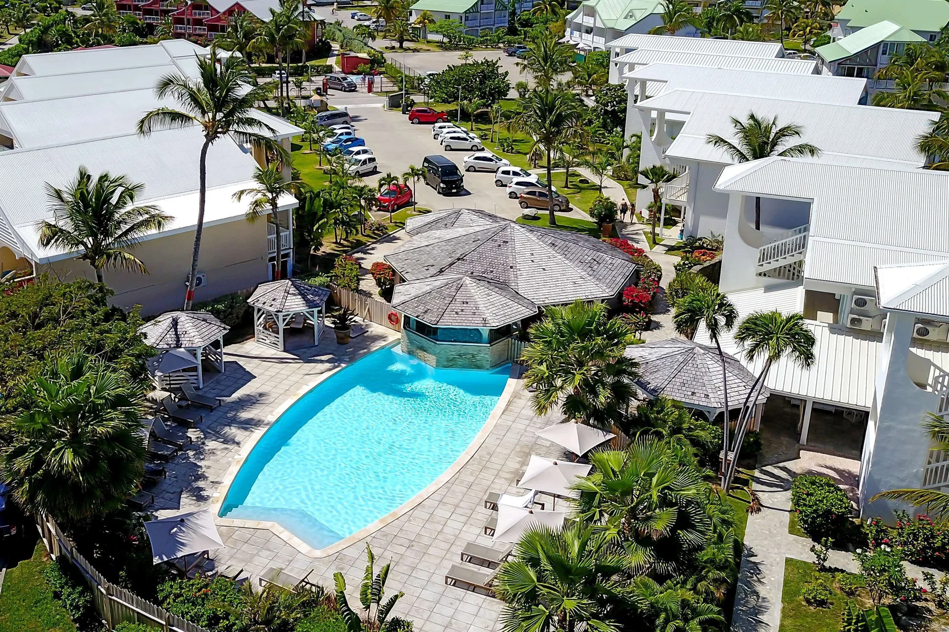 Aerial view of the pool, terraces, palms, and white buildings at La Playa Orient Bay.